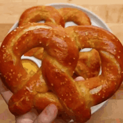 A Person Is Holding A Pretzel In Their Hand . GIF