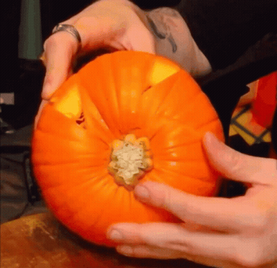 A Person Is Holding A Pumpkin With A Sticker That Says ' A ' On It GIF