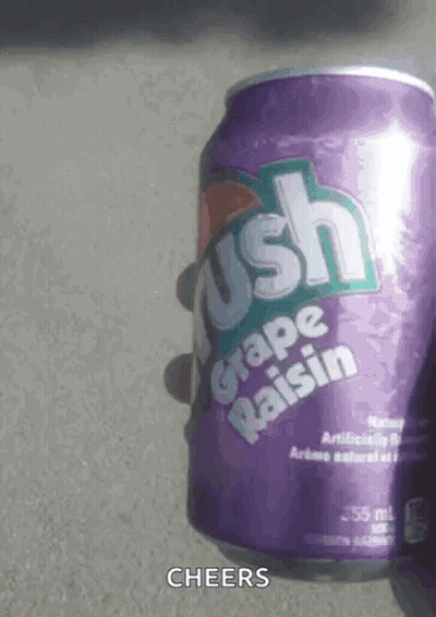 A Person Is Holding A Purple Can Of Grape Raisin Soda . GIF