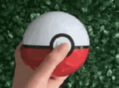 A Person Is Holding A Red And White Pokemon Ball In Their Hand . GIF