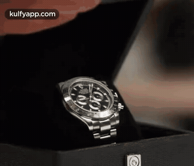 A Person Is Holding A Rolex Watch In A Black Box GIF