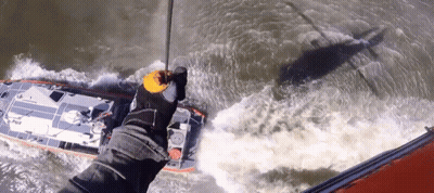 A Person Is Holding A Rope Over A Boat That Says ' Rescue ' On The Side GIF
