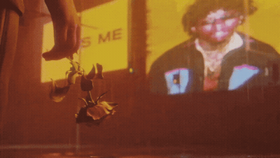 A Person Is Holding A Rose In Front Of A Sign That Says ' Kiss Me ' GIF