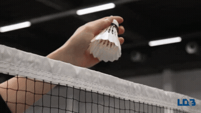 A Person Is Holding A Shuttlecock Over A Tennis Net GIF