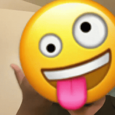 A Person Is Holding A Smiley Face With A Pink Tongue Sticking Out Of It . GIF