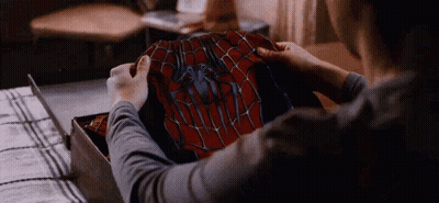 A Person Is Holding A Spider Man Costume In Their Hands . GIF