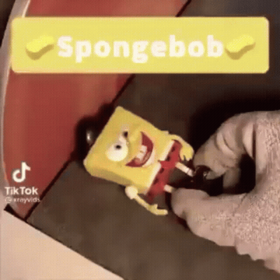 A Person Is Holding A Spongebob Toy In Their Hand And A Sign That Says Spongebob . GIF