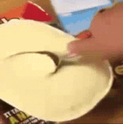 A Person Is Holding A Spoon In A Bowl Of Food .. GIF
