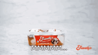 A Person Is Holding A Spoon Over A Container Of Friendly 'S Peanut Butter Fudge . GIF
