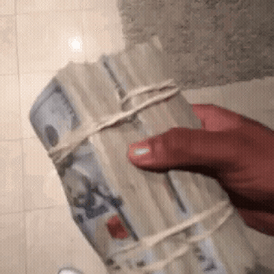 A Person Is Holding A Stack Of Money Wrapped In String . GIF