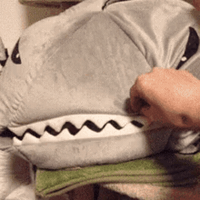 A Person Is Holding A Stuffed Animal That Looks Like A Shark . GIF
