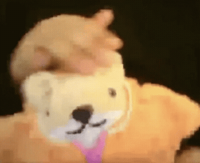 A Person Is Holding A Stuffed Animal That Looks Like A Teddy Bear With A Pink Tie Around Its Neck . GIF