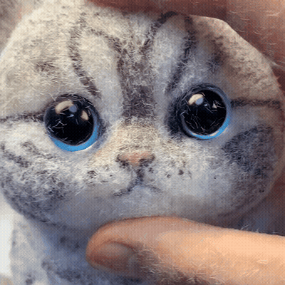 A Person Is Holding A Stuffed Cat With Blue Eyes GIF