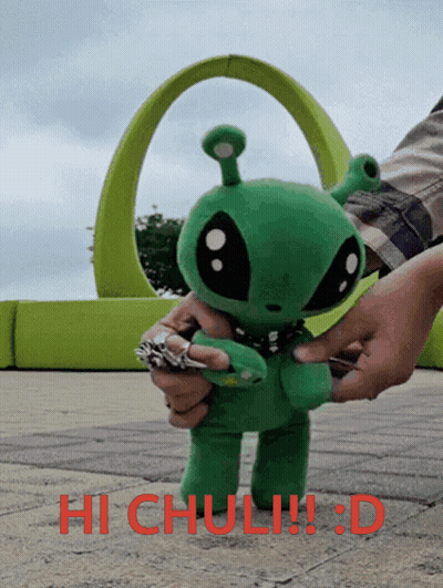 A Person Is Holding A Stuffed Green Alien With The Words Hi Chuli !!! D Written On The Bottom GIF