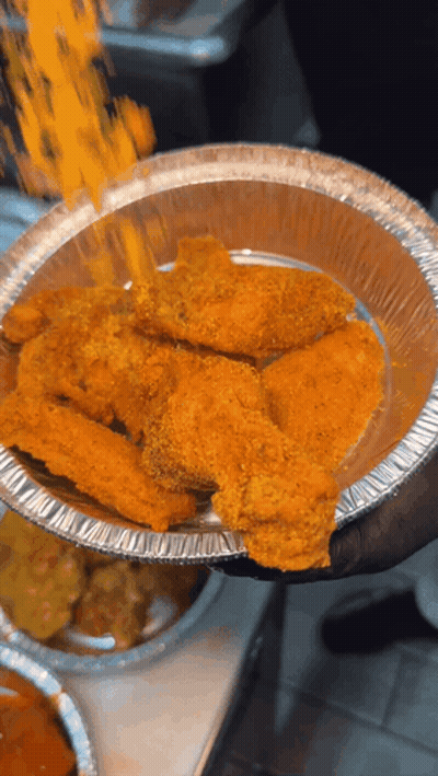 A Person Is Holding A Tin Foil Container Of Chicken Wings GIF
