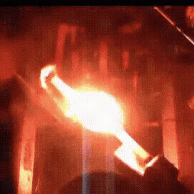 A Person Is Holding A Torch In A Dark Room With A Flame Coming Out Of It . GIF