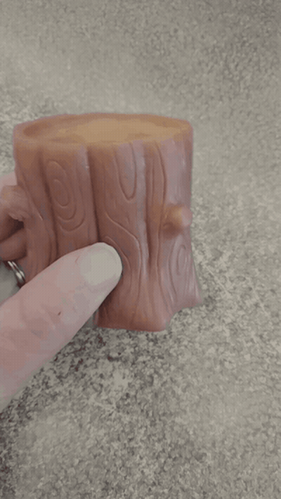 A Person Is Holding A Tree Stump With A Hole In The Middle GIF