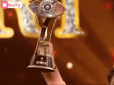A Person Is Holding A Trophy In Their Hand In Front Of A Stage . GIF