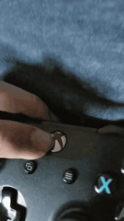 A Person Is Holding A Video Game Controller With A Blue X Button On It GIF