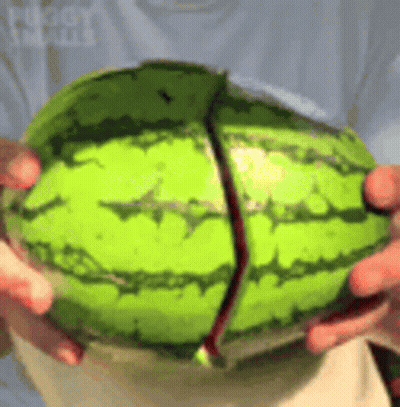 A Person Is Holding A Watermelon That Has Been Cut In Half And Is Being Held In Their Hands . GIF