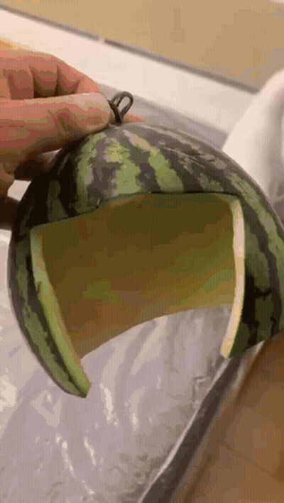A Person Is Holding A Watermelon With A Hole In It GIF