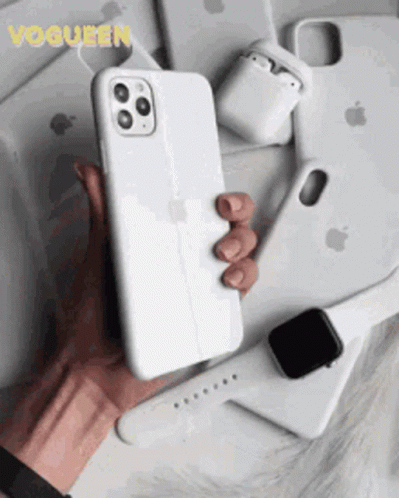 A Person Is Holding A White Iphone In Their Hand Surrounded By Apple Products . GIF