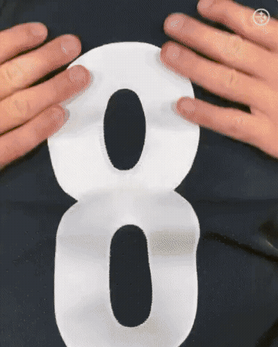A Person Is Holding A White Number 8 On Their Shirt GIF