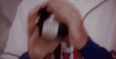 A Person Is Holding A White Object In Their Mouth With The Letter H On Their Shirt GIF