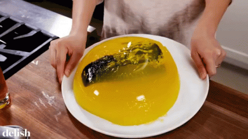 A Person Is Holding A White Plate With A Yellow Liquid On It And The Word Delish Is On The Bottom GIF