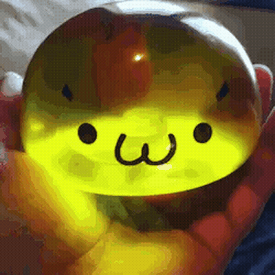 a person is holding a yellow sphere with a face on it .
