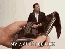 A Person Is Holding An Empty Wallet With A Man In A Suit Inside Of It . GIF