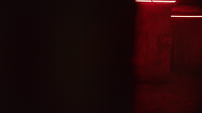 A Person Is Holding Something In Their Hands In A Dark Room With Red Lights GIF