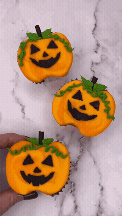 A Person Is Holding Three Cupcakes Decorated To Look Like Pumpkins For Halloween GIF