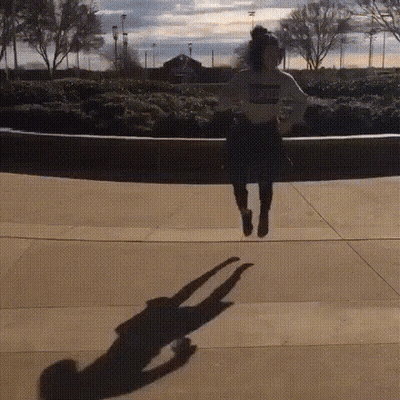 A Person Is Jumping In The Air And Their Shadow Is Visible . GIF