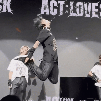A Person Is Jumping In The Air In Front Of A Sign That Says " Act Love " GIF
