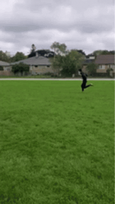 A Person Is Jumping In The Air On A Grassy Field . GIF