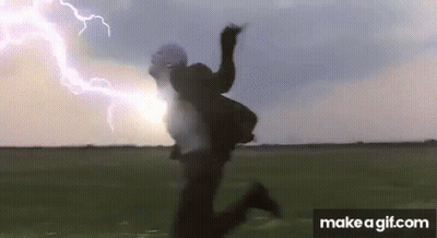 A Person Is Jumping In The Air While A Lightning Bolt Is Coming Down The Sky . GIF