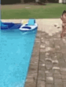 A Person Is Jumping Into A Swimming Pool With A Raft In The Water GIF