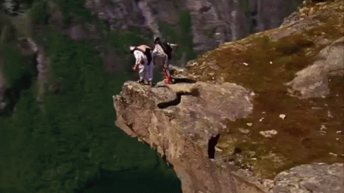 A Person Is Jumping Off A Cliff Into A Body Of Water GIF