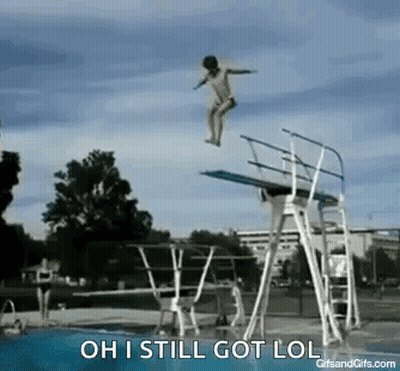 A Person Is Jumping Off Of A Diving Board Into A Pool . GIF