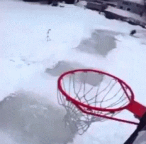 A Person Is Jumping Over A Basketball Hoop In The Snow .. GIF