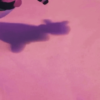 A Person Is Kneeling Down On A Pink Surface With A Purple Shadow On It . GIF