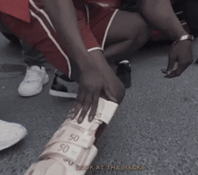 A Person Is Kneeling Down With A Stack Of Money On Their Leg GIF