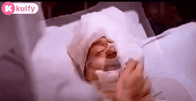 A Person Is Laying In A Hospital Bed With An Oxygen Mask On . GIF