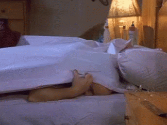 A Person Is Laying In Bed With Their Feet Sticking Out Of The Sheets GIF
