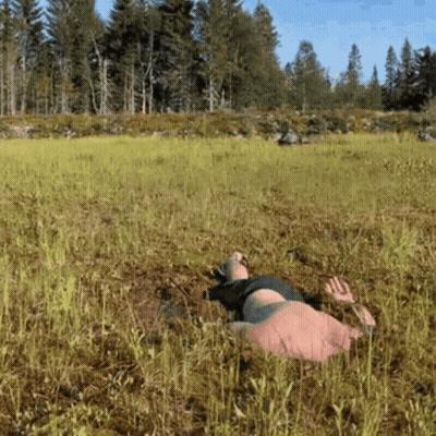 A Person Is Laying In The Grass In A Field GIF