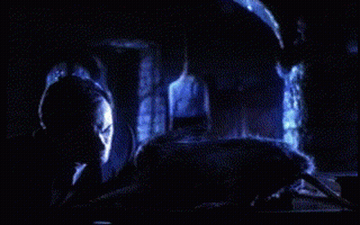A Person Is Laying On A Bed In A Dark Room With A Blue Light Behind Them GIF
