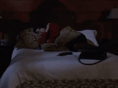 A Person Is Laying On A Bed With A Purse On The Floor GIF