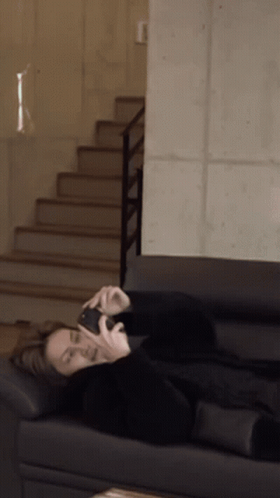 A Person Is Laying On A Couch Talking On A Cell Phone GIF