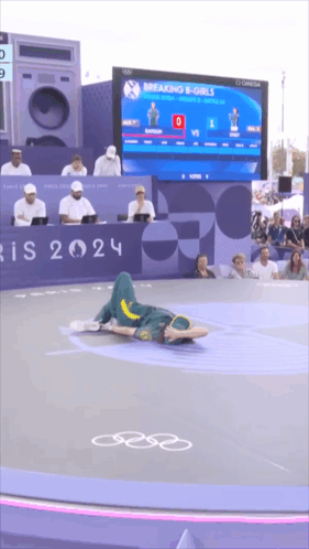 A Person Is Laying On The Floor In Front Of A Breaking B-Girls Sign GIF